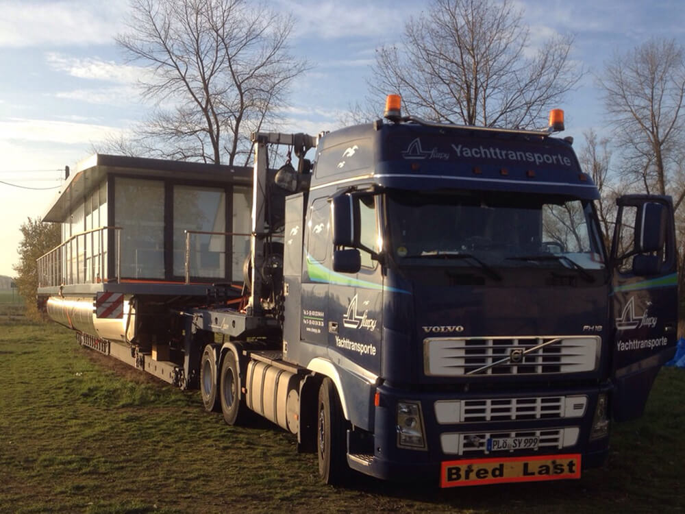 Sleepy Fahrzeug mit geladenem Hausboot | Sleepy Yachttransporte & Spezialtransporte
