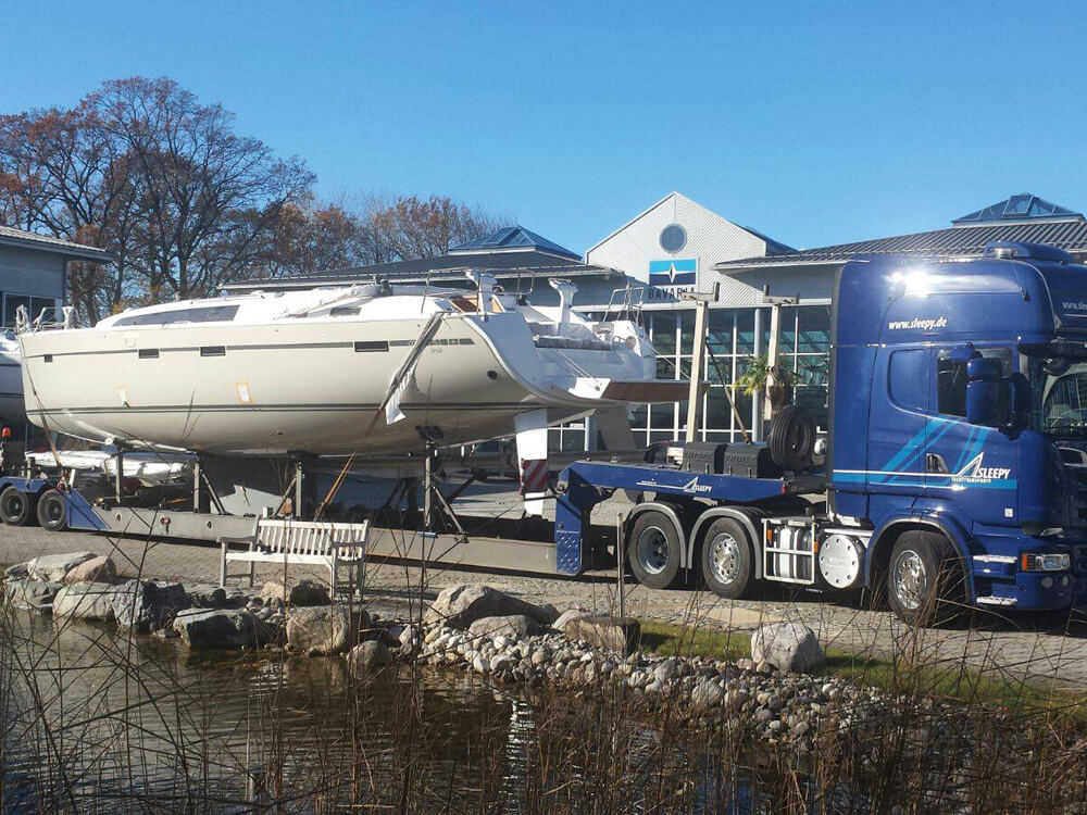Sleepy Fahrzeug mit geladener Yacht am Wasser | Sleepy Yachttransporte & Spezialtransporte